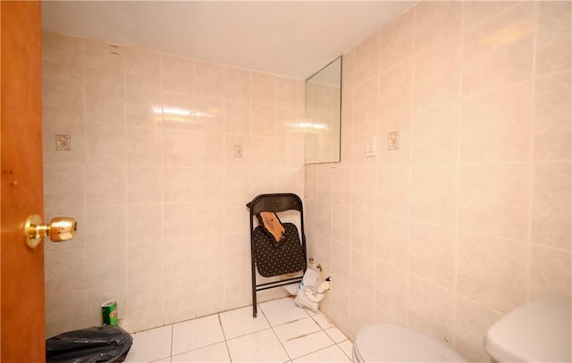 bathroom with tile patterned flooring, toilet, and tile walls