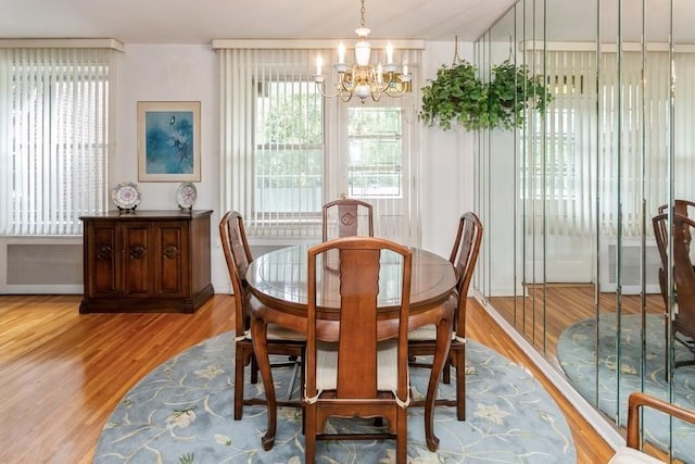 dining space with an inviting chandelier, radiator heating unit, and light hardwood / wood-style flooring