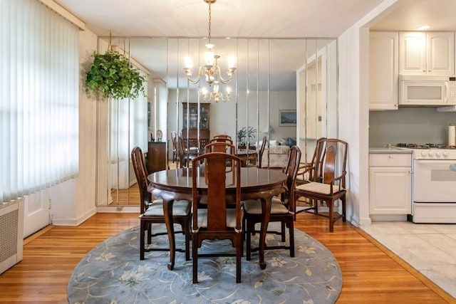 dining room featuring radiator heating unit, a chandelier, and light wood-type flooring