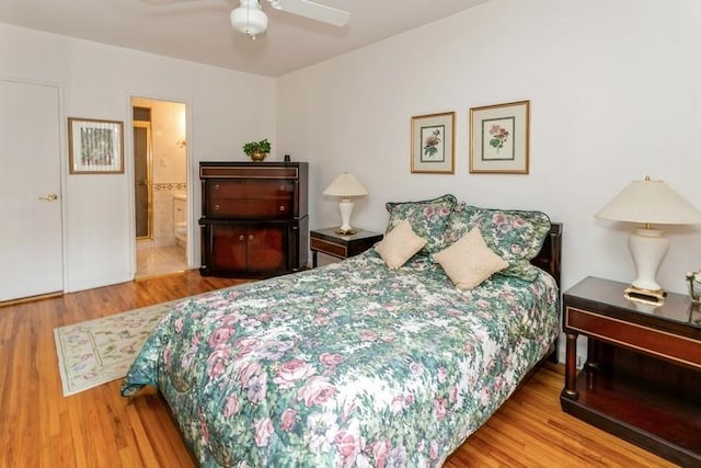 bedroom featuring ceiling fan, ensuite bath, and light wood-type flooring