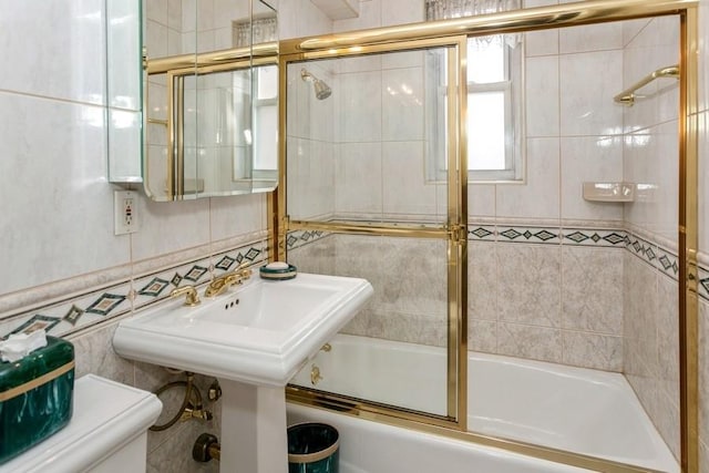 full bathroom with toilet, sink, combined bath / shower with glass door, tasteful backsplash, and tile walls