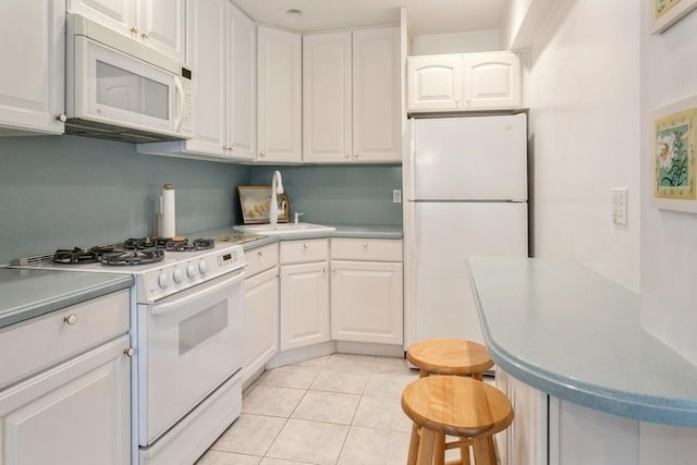 kitchen featuring sink, a breakfast bar area, light tile patterned floors, white appliances, and white cabinets