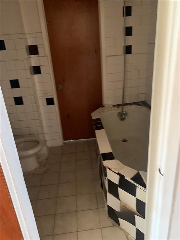 bathroom featuring tile patterned floors, toilet, and a bath