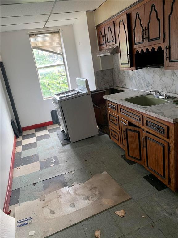 kitchen featuring tasteful backsplash, a paneled ceiling, and sink