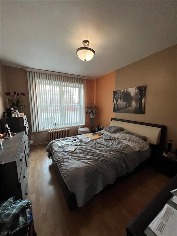 bedroom with radiator and hardwood / wood-style flooring