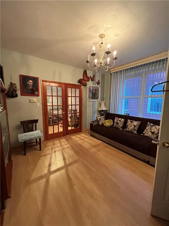 sitting room featuring an inviting chandelier, french doors, and wood-type flooring