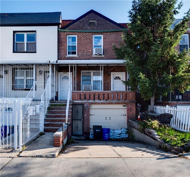 view of property featuring brick siding, driveway, an attached garage, and fence