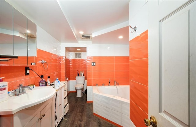 full bath featuring a garden tub, tile walls, toilet, vanity, and wood finished floors