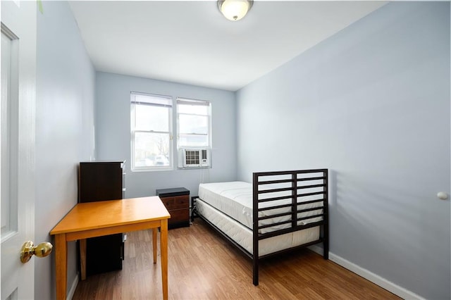 bedroom featuring cooling unit, wood finished floors, and baseboards