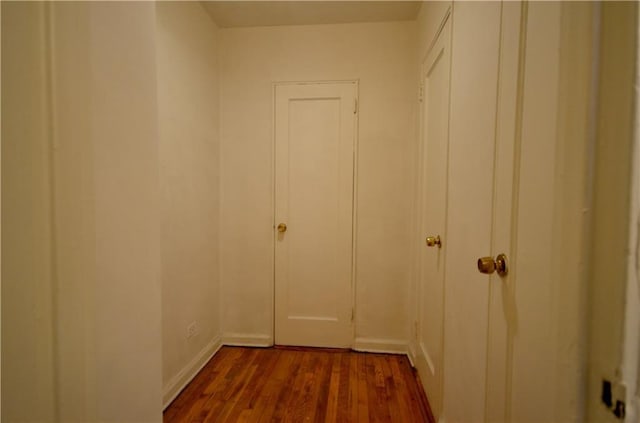 corridor with baseboards and wood finished floors