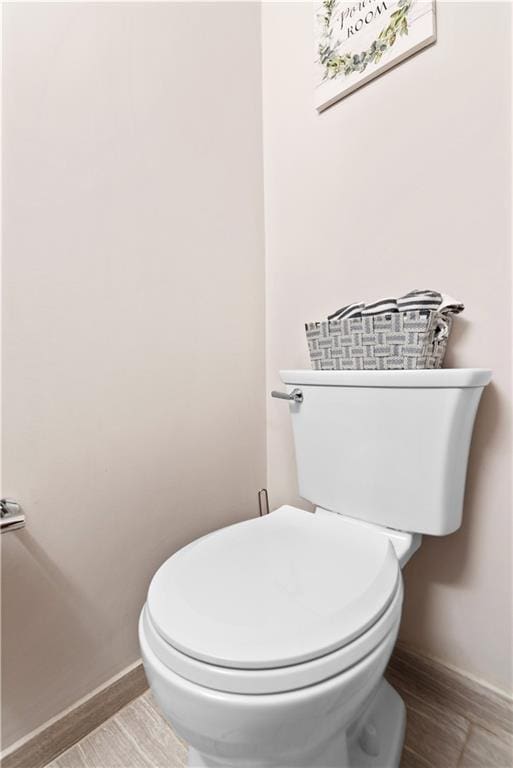 bathroom with baseboards, toilet, and wood finished floors