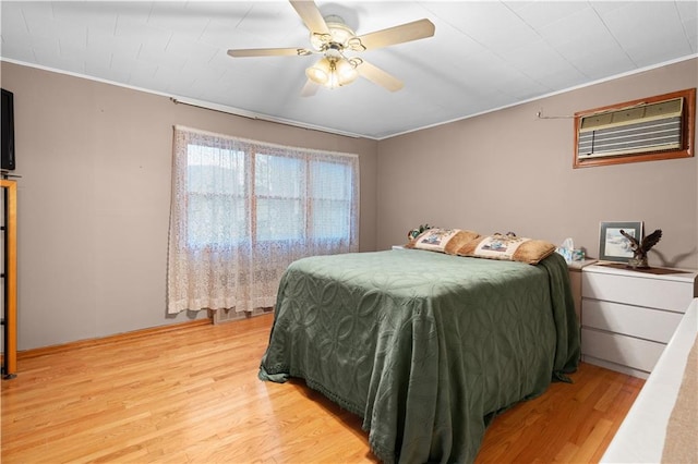 bedroom featuring ornamental molding, a wall mounted air conditioner, ceiling fan, and light wood finished floors