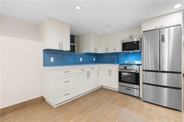 kitchen with white cabinetry, appliances with stainless steel finishes, light countertops, and a sink