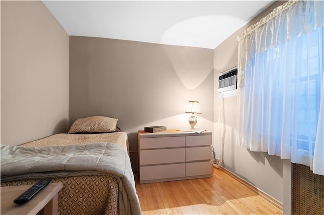 bedroom featuring a wall mounted air conditioner and light wood finished floors