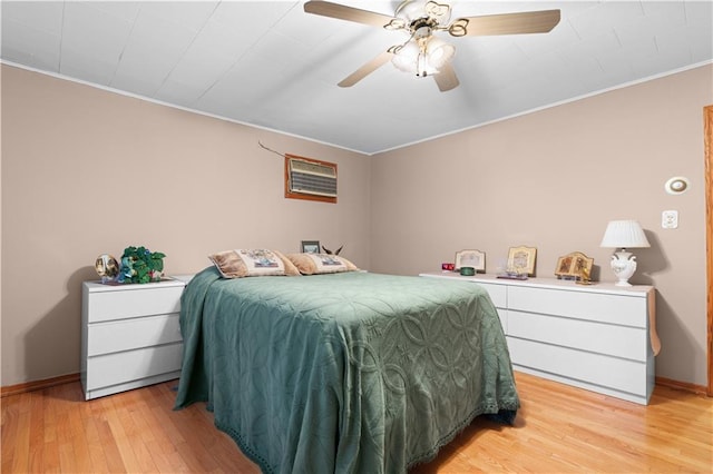 bedroom featuring an AC wall unit, ornamental molding, light wood-style flooring, and baseboards