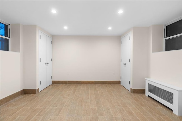 interior space with light wood-type flooring, baseboards, radiator heating unit, and recessed lighting