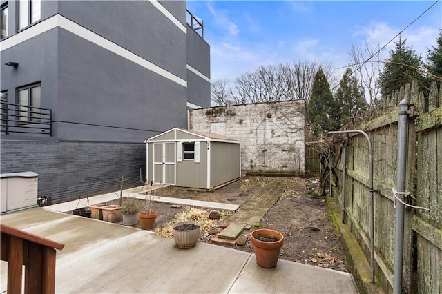 exterior space with a fenced backyard, a storage unit, a patio, and an outbuilding