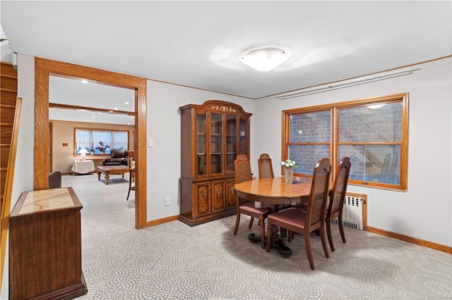 dining space featuring radiator, baseboards, and light colored carpet