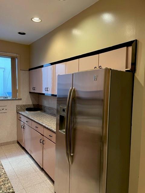 kitchen featuring white cabinetry, light stone countertops, and stainless steel fridge