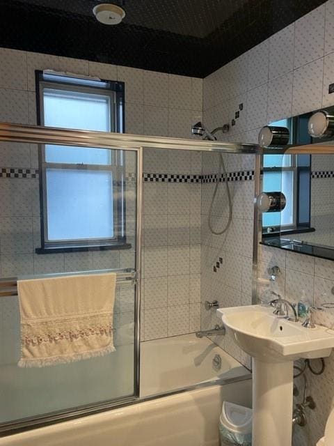 bathroom featuring combined bath / shower with glass door and backsplash