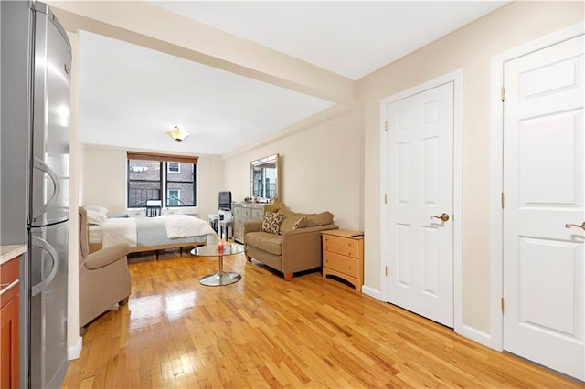 bedroom with stainless steel fridge and light wood-type flooring