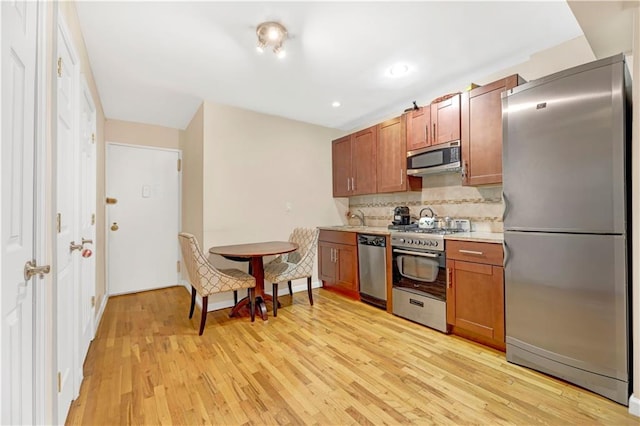 kitchen featuring stainless steel appliances, light hardwood / wood-style flooring, tasteful backsplash, and sink