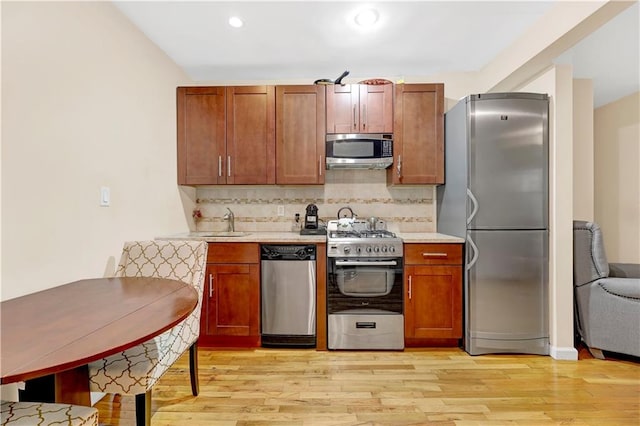 kitchen with light hardwood / wood-style floors, sink, appliances with stainless steel finishes, and tasteful backsplash