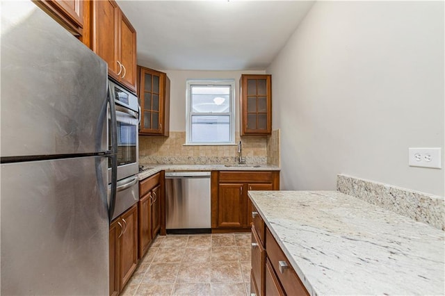 kitchen featuring decorative backsplash, brown cabinets, appliances with stainless steel finishes, a warming drawer, and a sink