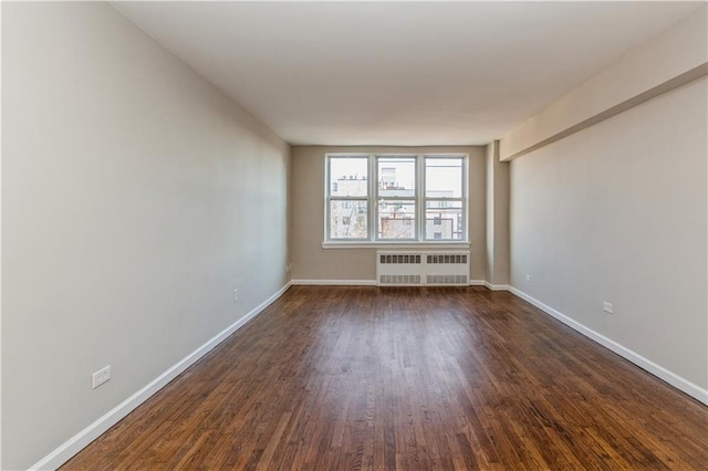 empty room with baseboards, dark wood-type flooring, and radiator heating unit