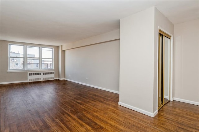 unfurnished room with radiator, baseboards, and dark wood-style flooring