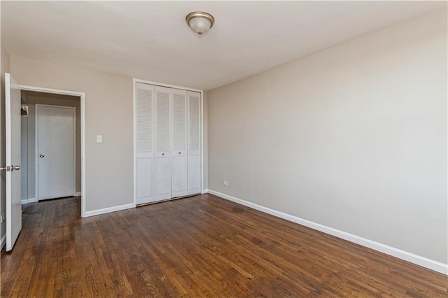 unfurnished bedroom with a closet, dark wood finished floors, and baseboards