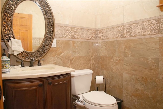 bathroom with vanity, toilet, and tile walls