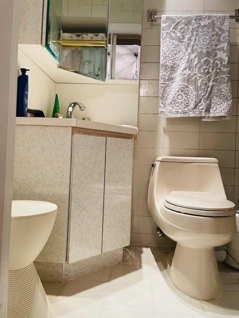 bathroom featuring tile patterned floors, toilet, and tile walls