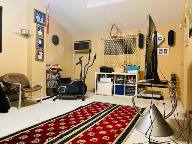 exercise area featuring lofted ceiling, carpet flooring, and an AC wall unit