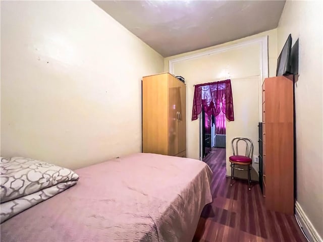 bedroom featuring radiator heating unit and dark hardwood / wood-style flooring