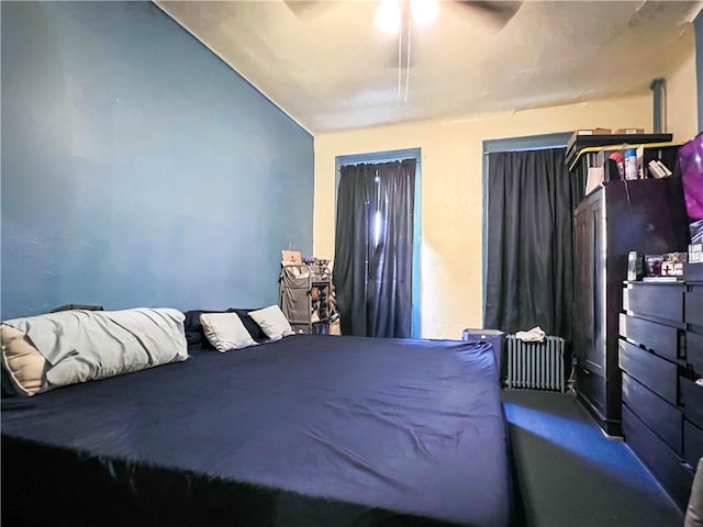 carpeted bedroom with radiator, vaulted ceiling, and ceiling fan