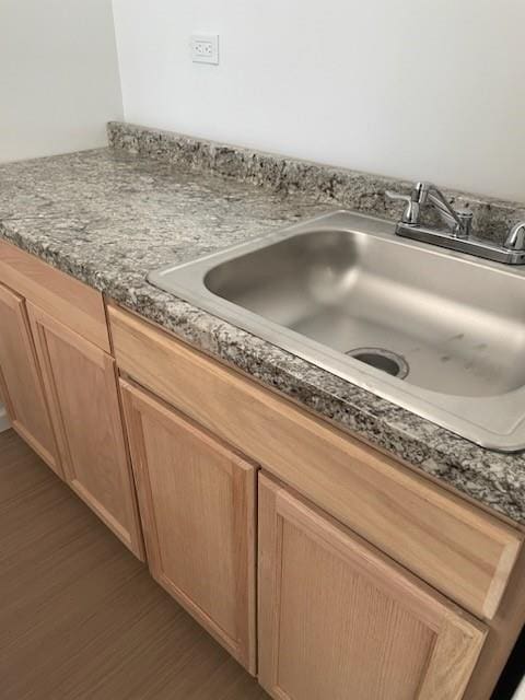 details with dark stone countertops, a sink, and dark wood finished floors