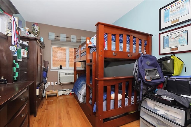 bedroom with light hardwood / wood-style flooring and a wall unit AC