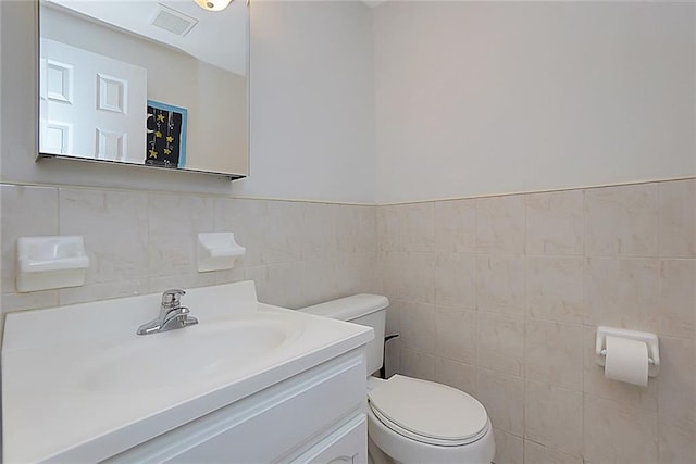 bathroom with vanity, tile walls, and toilet