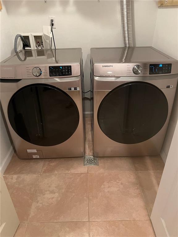 laundry room with washer and dryer and light tile patterned floors