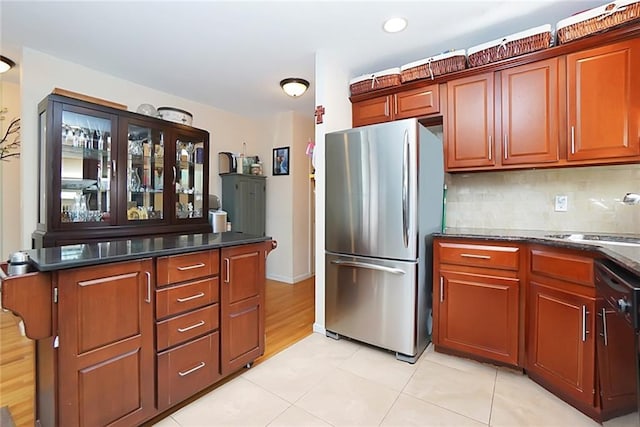 kitchen with light tile patterned floors, tasteful backsplash, dishwasher, freestanding refrigerator, and a sink