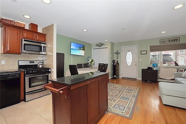 kitchen with stainless steel appliances, backsplash, and light wood-type flooring