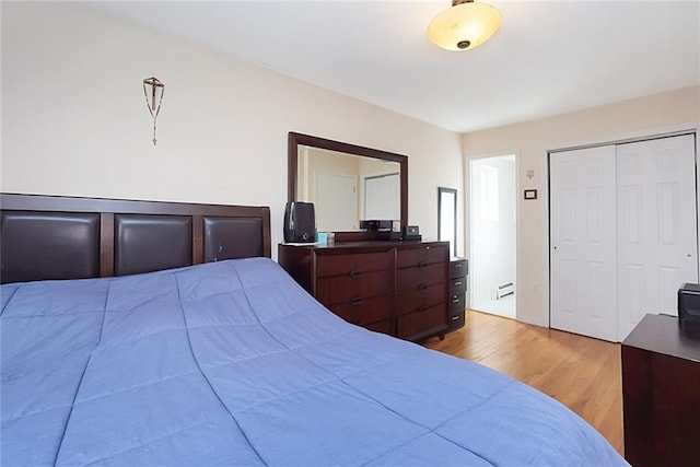 bedroom with light hardwood / wood-style floors, a closet, and a baseboard heating unit