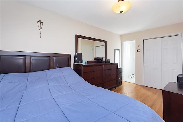 bedroom with wood finished floors, a baseboard radiator, and a closet