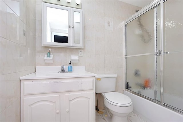 full bath with tile walls, bath / shower combo with glass door, vanity, toilet, and tile patterned flooring