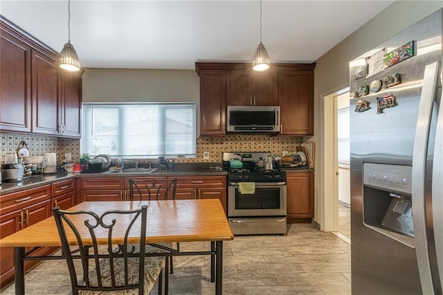 kitchen with dark stone counters, hanging light fixtures, and appliances with stainless steel finishes