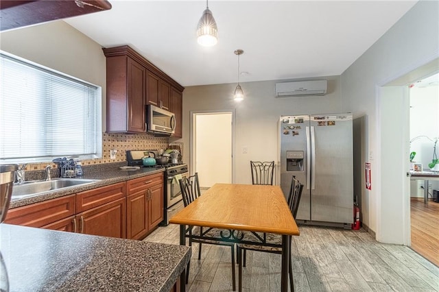 kitchen featuring a wall mounted air conditioner, sink, stainless steel appliances, and hanging light fixtures