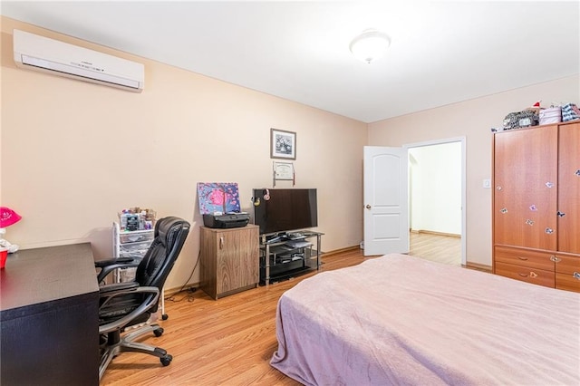 bedroom with an AC wall unit and light hardwood / wood-style flooring