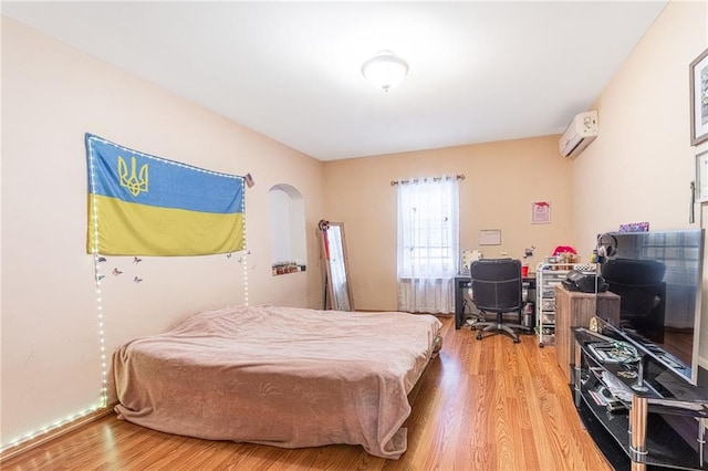 bedroom featuring hardwood / wood-style floors and an AC wall unit