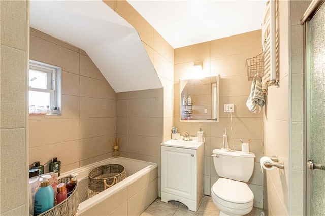 bathroom featuring tile patterned floors, vanity, vaulted ceiling, tile walls, and toilet